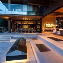 steel lift &amp; slide doors open, exterior view looking into dining area at dusk