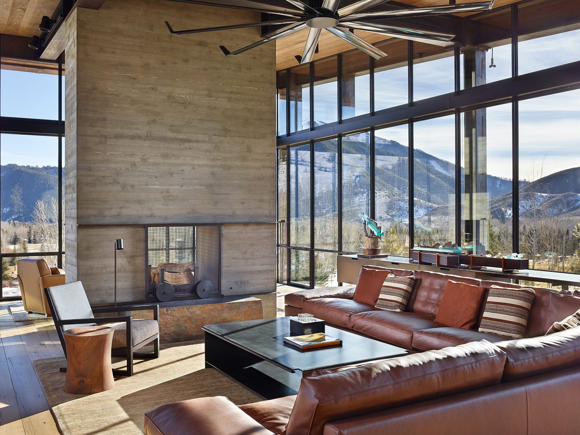 Massive fireplace, couches and steel residential storefront windows in background