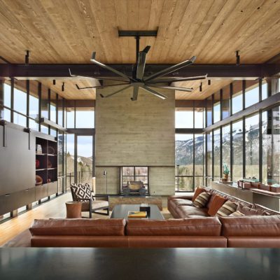 Metal framed residential storefront windows surround living room in mountain home