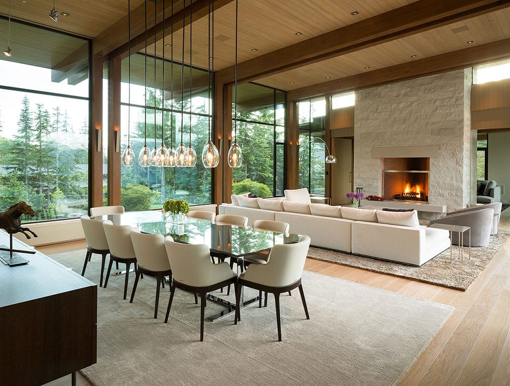 Living room table with large massive steel windows in background of modern home