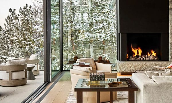Reynaers Aluminum lift and slide doors with fireplace and snowy exterior visible through glass