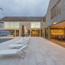 AML Architecture – Sag Harbor Massive wood lift and slide doors open to patio on the water