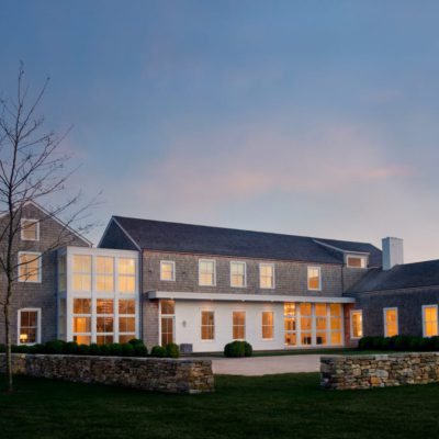 Interior-lit luxury home with custom wood windows at twilight