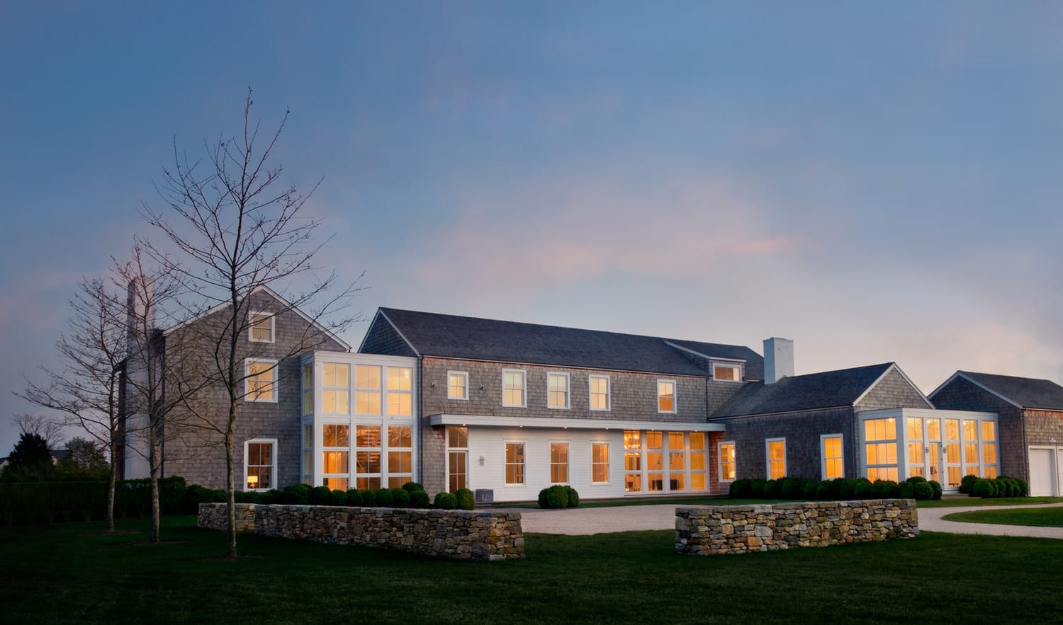 Interior-lit luxury home with custom wood windows at twilight