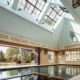 Multi-panel wood bifold door reveals large opening to outside from indoor pool