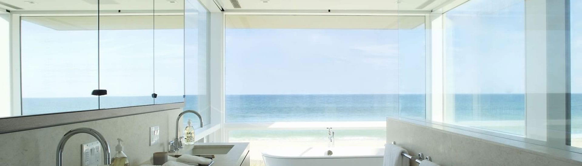 Massive glass window overlooking the sea through a bathroom