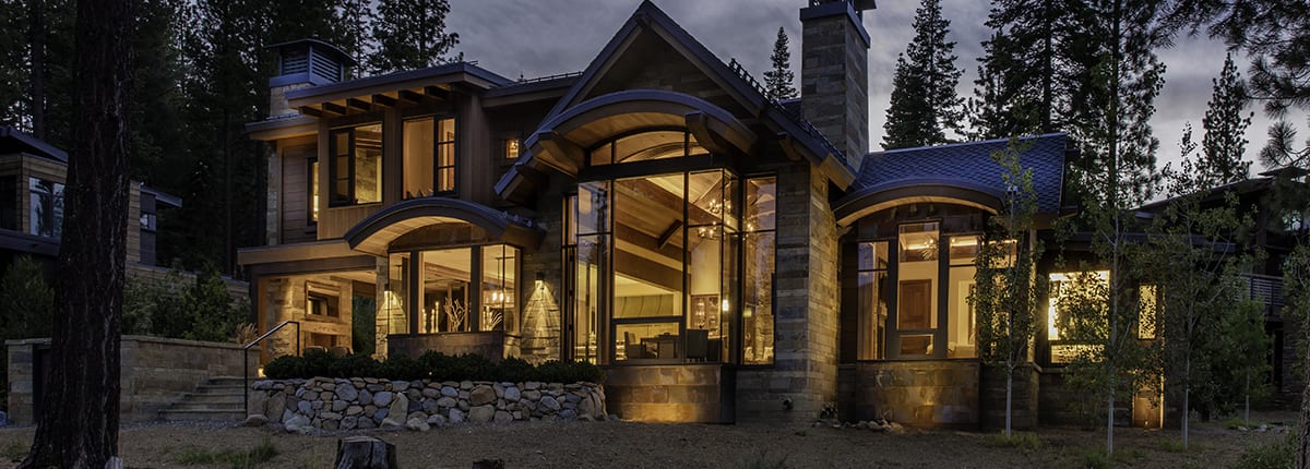 Exterior night view of modern mountain home with tall wood windows