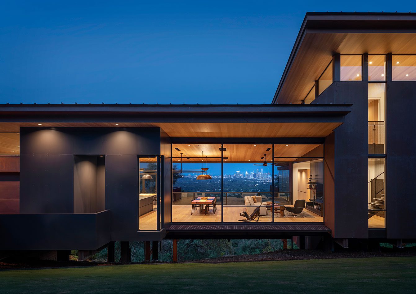 Exterior night view of lighted modern home with residential window walls
